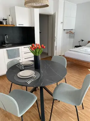 a black table with chairs and a vase of flowers at HAY Apartment Bled in Bled