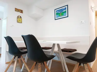 a white table with four black chairs in a room at Siesta apartment Bled in Bled