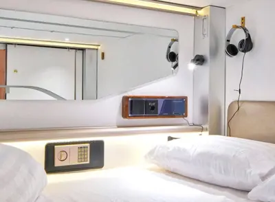 a room with a bed with a mirror and a clock at Ljubljana Capsule Hostel in Ljubljana