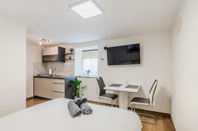 a bedroom with a bed and a desk and a kitchen at Apartmaji Mouse in Bovec