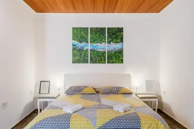 a white bedroom with a bed with two windows at Apartmaji Mouse in Bovec