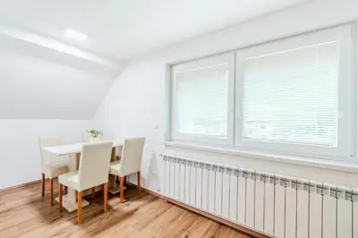 a white dining room with a table and chairs and a window at Apartmaji Mouse in Bovec