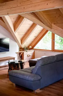 a living room with a blue couch and wooden ceilings at Apartma Mlekuž in Bovec