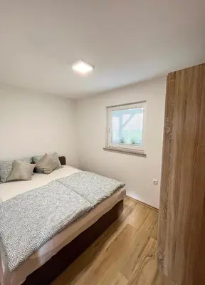 a bedroom with a bed and a window at Holiday House Tomajna in Podlehnik
