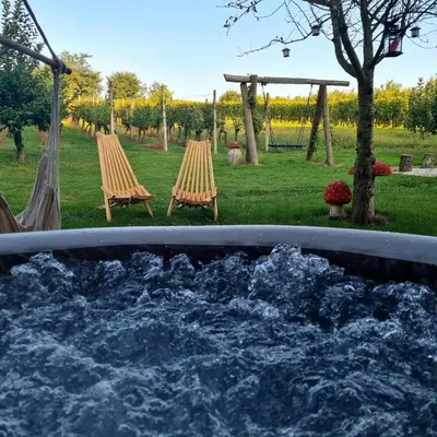a hot tub with two chairs and a water fountain at Gozdarjeva hiška M&K in Dobrovnik