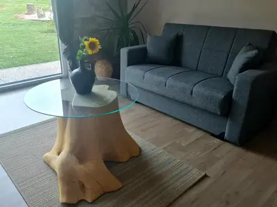a living room with a glass table and a couch at Gozdarjeva hiška M&K in Dobrovnik