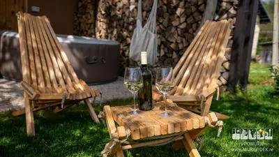 two wooden chairs with wine glasses on a table at Gozdarjeva hiška M&K in Dobrovnik