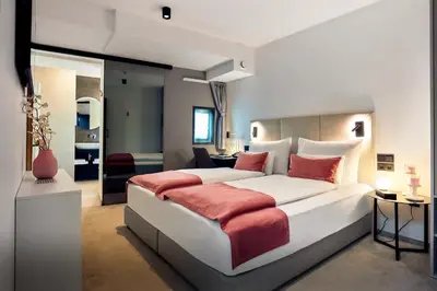 a bedroom with a large white bed with red pillows at The Hotel Ljubljana in Ljubljana