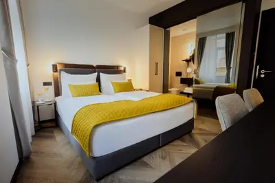 a bedroom with a large bed with a yellow blanket at The Hotel Ljubljana in Ljubljana