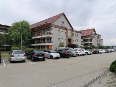 a parking lot with cars parked in front of a building at Apartma Petja in Moravske Toplice