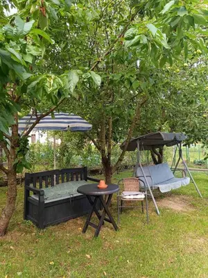 a table and a chair and an umbrella and a swing at Sobe pri Roži in Postojna
