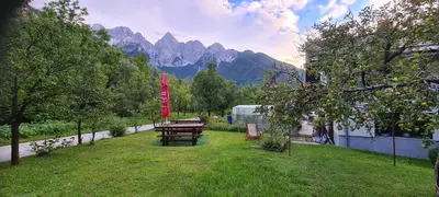 a picnic table in a field with mountains in the background at Apartma Vidic in Gozd Martuljek