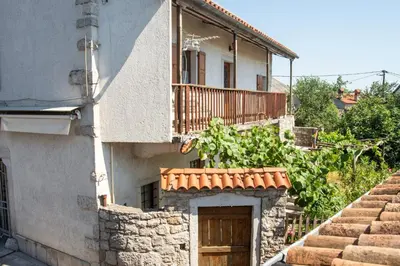 a building with a wooden door and a balcony at Apartma Na skdnu in Dutovlje