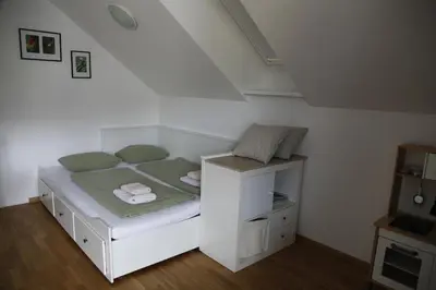 a small white bed in a room with a staircase at Family apartment on Repečnik farm in Gorje, Bled in Zgornje Gorje