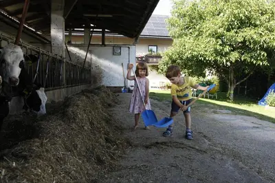 a boy and a girl playing with paddles in front of a cow at Family apartment on Repečnik farm in Gorje, Bled in Zgornje Gorje