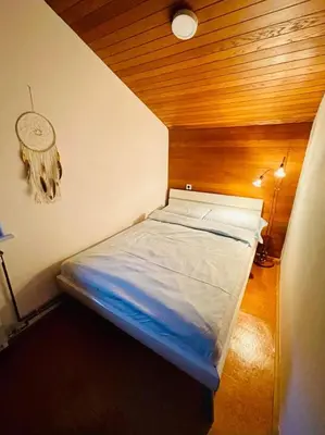 a small bed in a room with a wooden ceiling at Apartma Kamra15 in Mežica