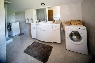 a bathroom with a washing machine and a sink at Apartma Kamra15 in Mežica