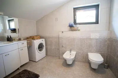 a bathroom with a washing machine and a toilet at Apartma Kamra15 in Mežica