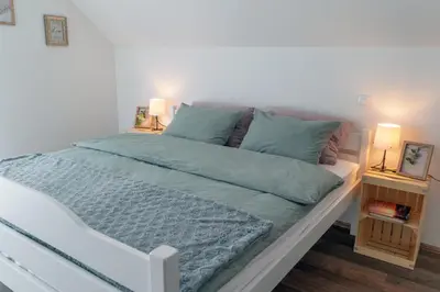 a bedroom with a bed with blue sheets and two lamps at Villa Cerkniško jezero in Cerknica