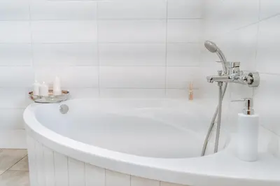 a white bath tub with a shower in a bathroom at Villa Cerkniško jezero in Cerknica