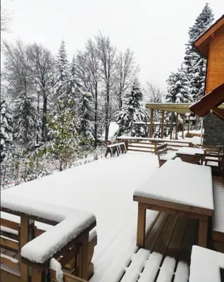 a snow covered patio with tables and benches at Prijeten sončen apartma v objemu Pohorja in Zgornje Hoče