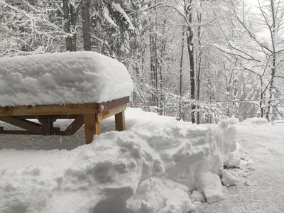 a pile of snow next to a wooden bench at Prijeten sončen apartma v objemu Pohorja in Zgornje Hoče