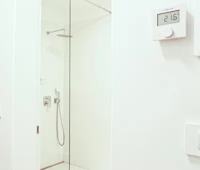 a shower in a bathroom with a clock on the wall at JU3 Apartments in Ljubljana