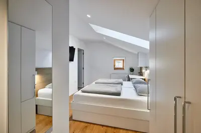 a white bedroom with a bed and a sliding door at Fine Rooms Vipava in Vipava