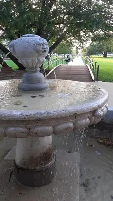 a stone fountain with a stream of water in a park at Fine Rooms Vipava in Vipava