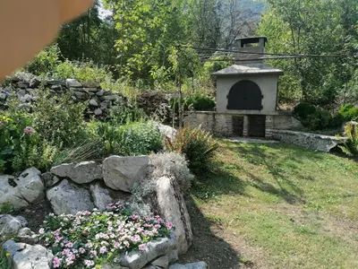 a garden with a stone fireplace and some flowers at APARTMAJI VALTER in Srpenica