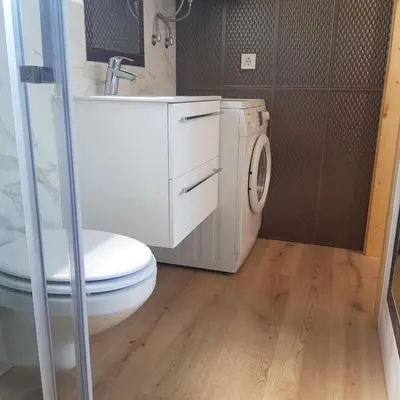 a bathroom with a toilet and a sink and a washing machine at Trg Mozirje in Mozirje