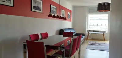 a dining room with a table and red chairs at city center park view appartment in Maribor