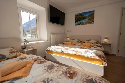 a bedroom with two beds and a tv on the wall at Relax House Soča in Bovec