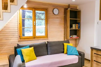 a living room with a couch with yellow and blue pillows at Chalet Liza & Rozi in Zgornja Ložnica