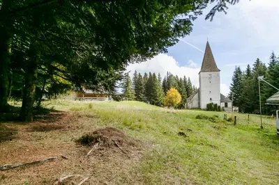 a church on top of a hill with a grassy field at Chalet Liza & Rozi in Zgornja Ložnica