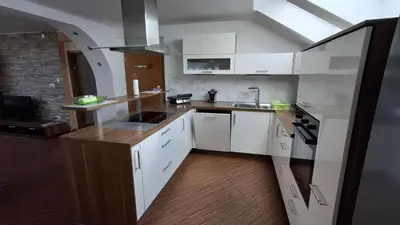 a kitchen with white cabinets and a wooden floor at Hiša Bizjak in Kranj