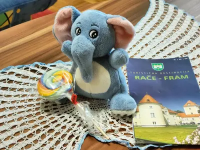 a stuffed elephant sitting on a table next to a book at Apartma Velesa in Rače