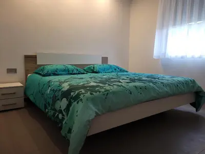 a bedroom with a bed with a green comforter and a window at Apartment river Nadiža Podbela in Podbela