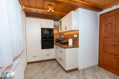 a kitchen with white cabinets and a wooden ceiling at Chalet Ajda in Bohinj