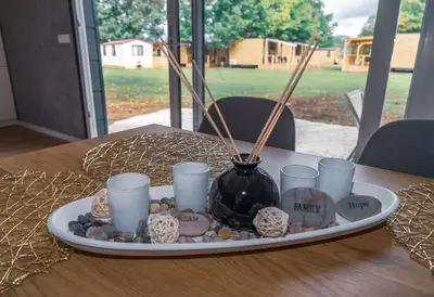 a plate with a vase and some cups on a table at Mobilna hiška pod Lipo in Velenje