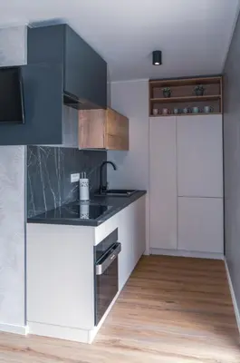 a kitchen with white cabinets and a black counter top at Mobilna hiška pod Lipo in Velenje