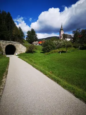 a path with a bridge and a building in the background at Valle Divina in Mislinja