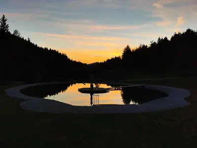a reflection of a boat in a lake at sunset at Valle Divina in Mislinja