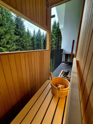 a sauna with a large window and a bucket on a bench at Green Garden House in Zreče