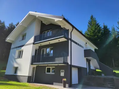a white building with black balconies at Green Garden House in Zreče