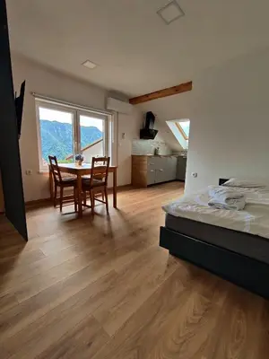 a bedroom with a bed and a table and chairs at Apartments and rooms pri Bašlju in Cerkno
