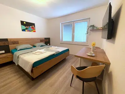 a bedroom with a bed and a table and a desk at Apartments and rooms pri Bašlju in Cerkno