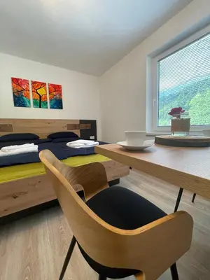 a room with a desk and chairs and a bed at Apartments and rooms pri Bašlju in Cerkno