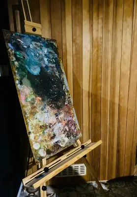 a painting on a stand next to a wooden wall at Rooms & Apartment ZALA Near Airport & Cable Car in Cerklje na Gorenjskem