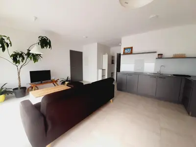 a living room with a couch and a kitchen at Green Bee Apartment in Lesce